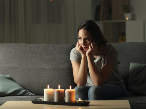 Woman sitting on the couch in the dark after a power surge/outage