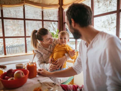 Portrait of a cheerful young family having breakfast in their cottage house on the countryside, while it is snowing outside